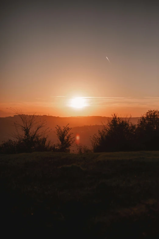 a sunset taken from a hilltop with a few clouds