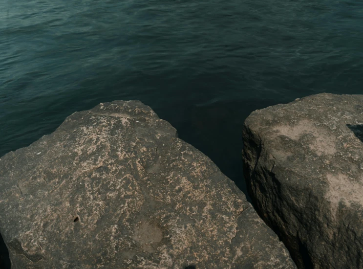 a couple of rocks by the water are being read by someone