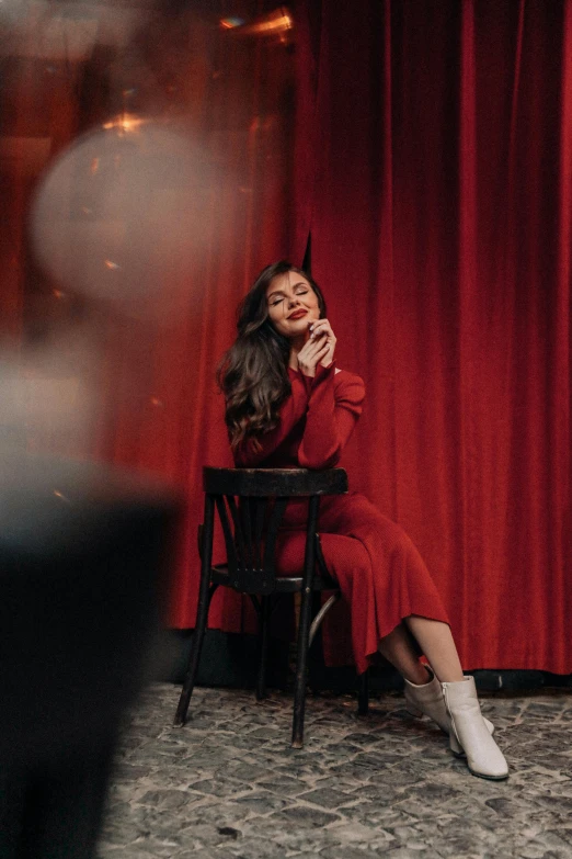 a woman in a devil costume is posing by a red curtain