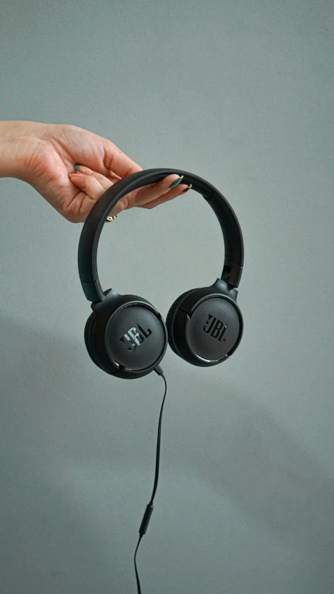 a person holding up two black headphones