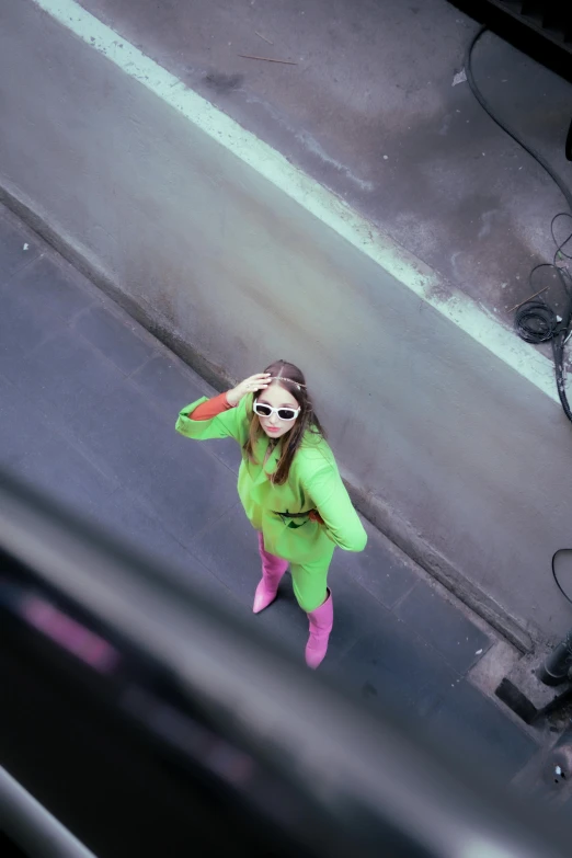 a young woman in green is standing on the street