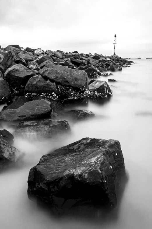 a long exposure of rocks and a light house