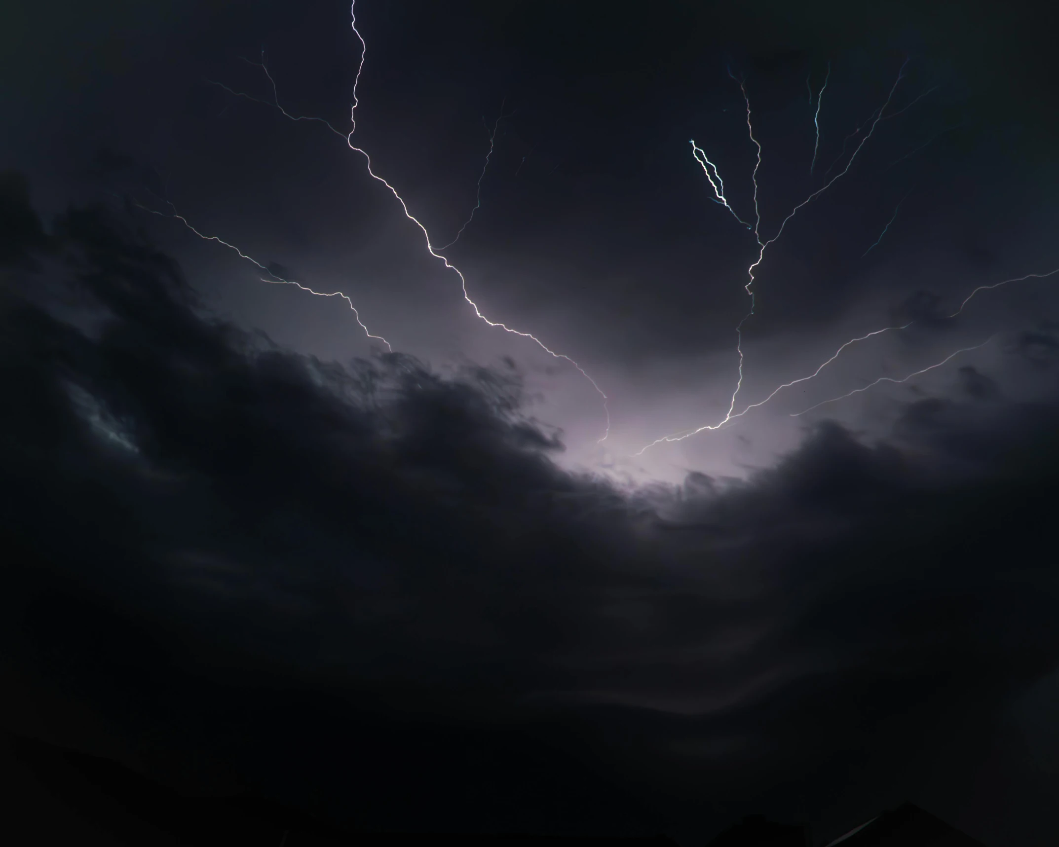 a lightning strike can be seen in the night sky