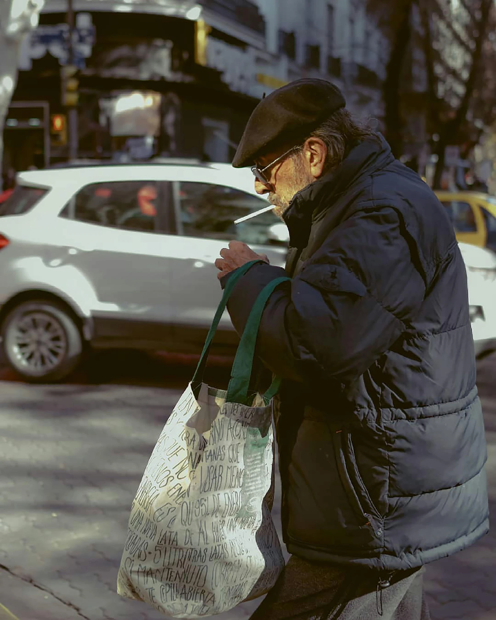 a man with a black coat, black hat and a bag