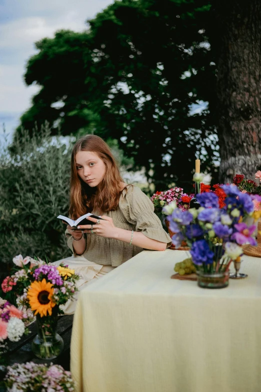 girl reads a book at the table surrounded by a tree