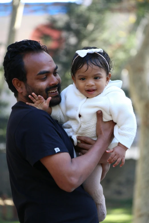 a man carrying a little girl up to his face