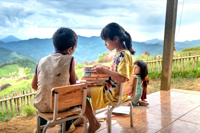 children sit around a desk with books and magazines on the ground