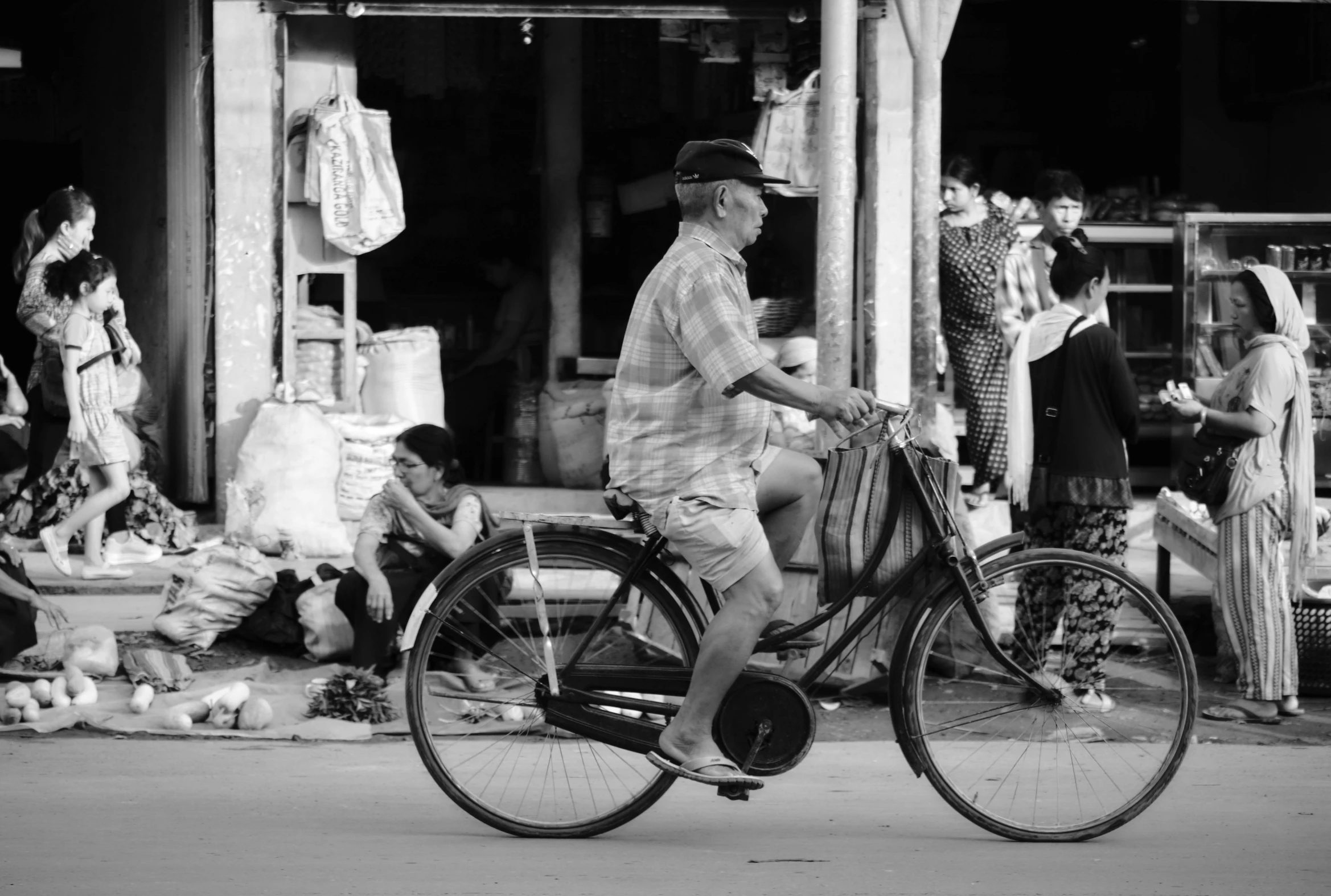 an elderly man is riding a bicycle past small shops