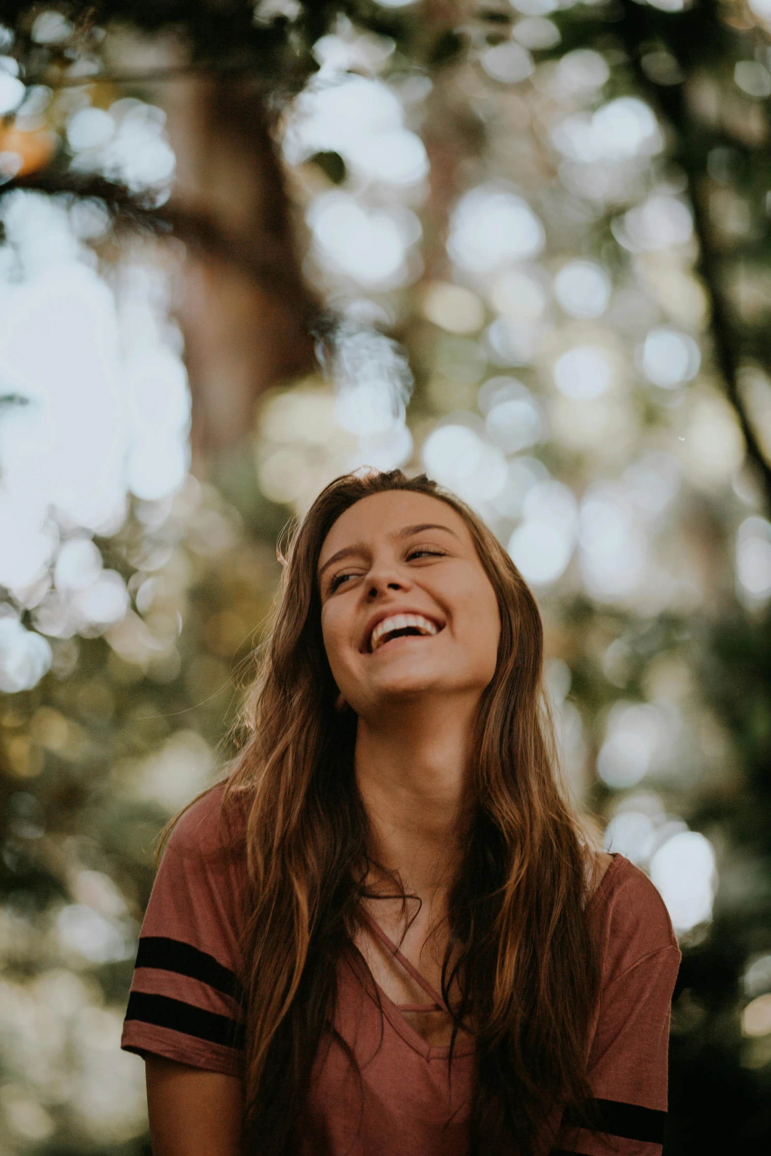 smiling woman laughing in the trees at an outdoor park