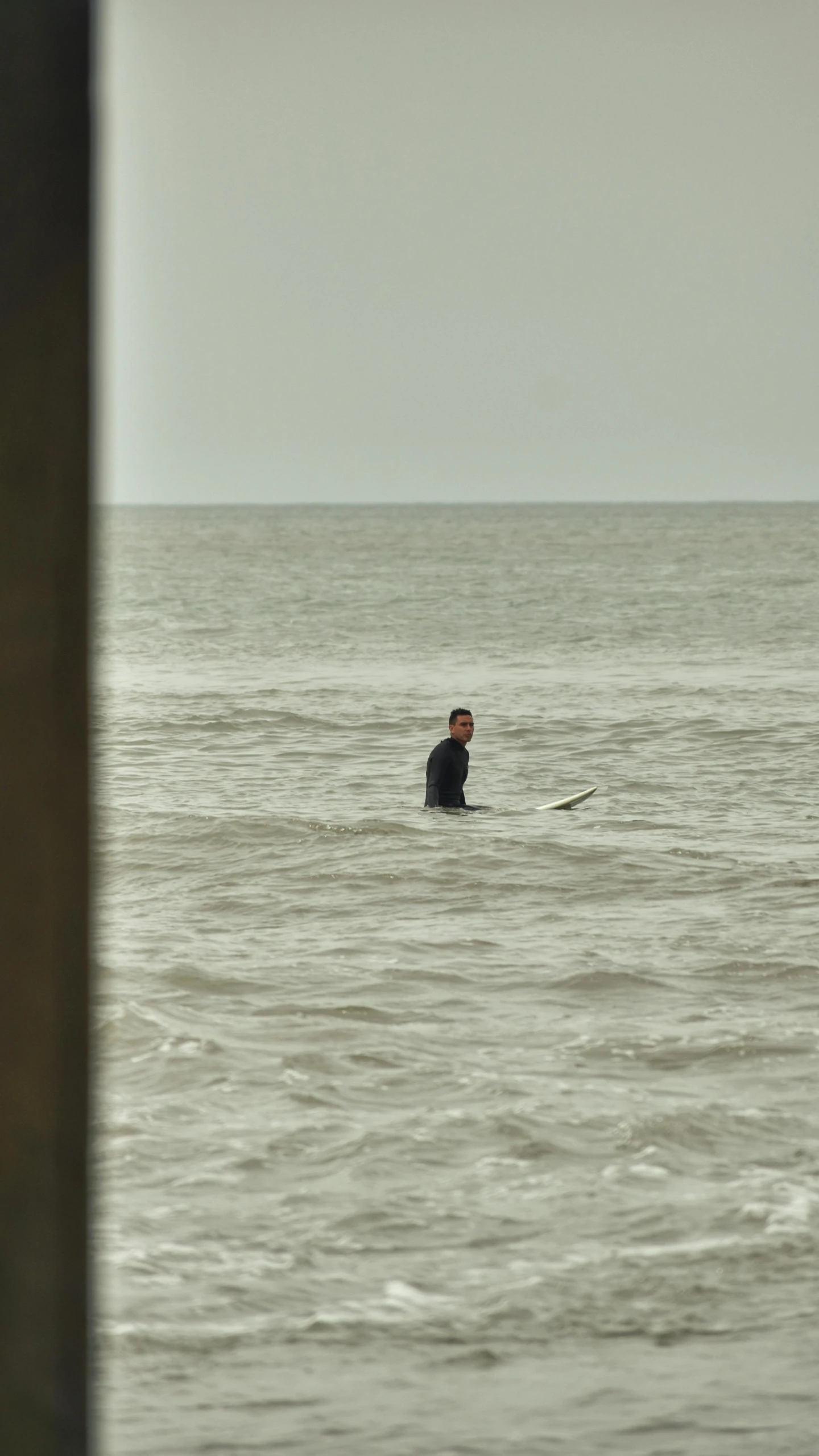 a man standing in the ocean holding onto a surfboard