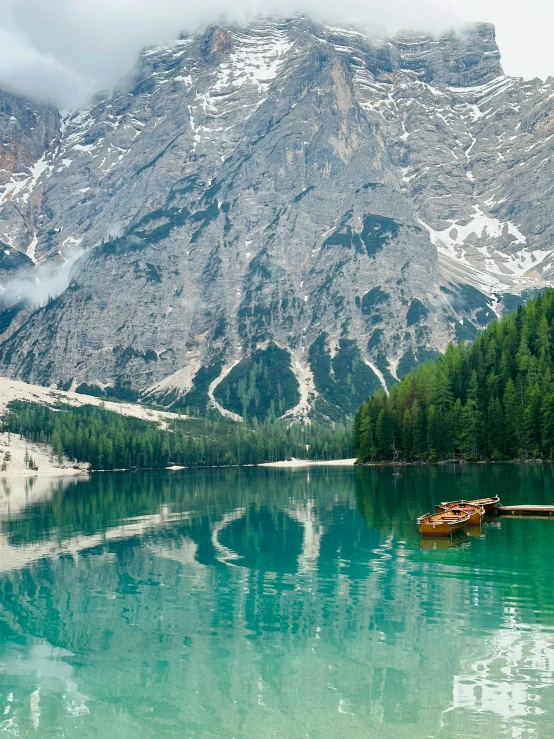 two small boats floating on a lake surrounded by mountains