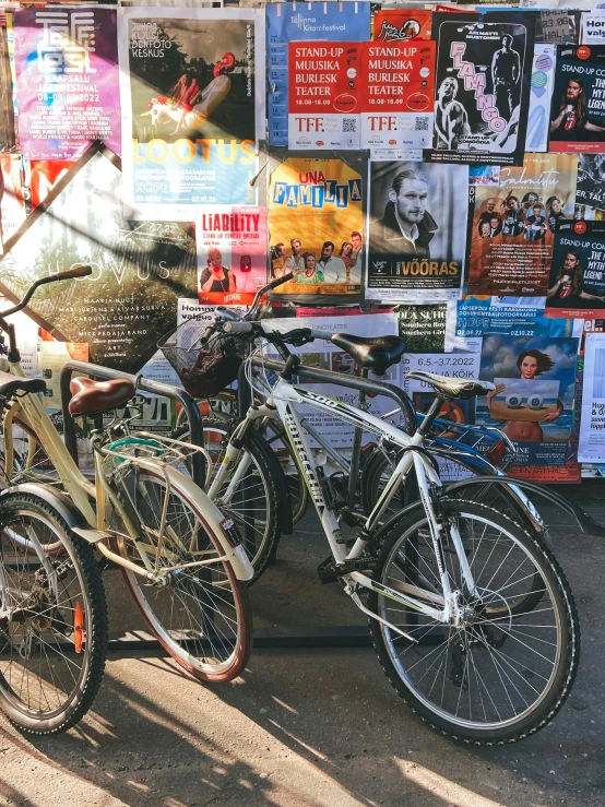 several bikes parked in front of a wall with posters on it