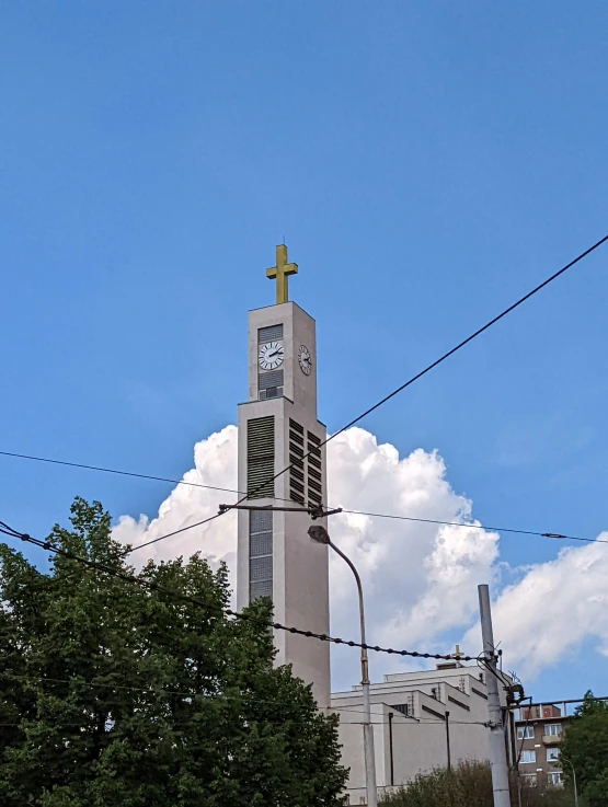 a church with a cross atop the roof, in front of a blue sky