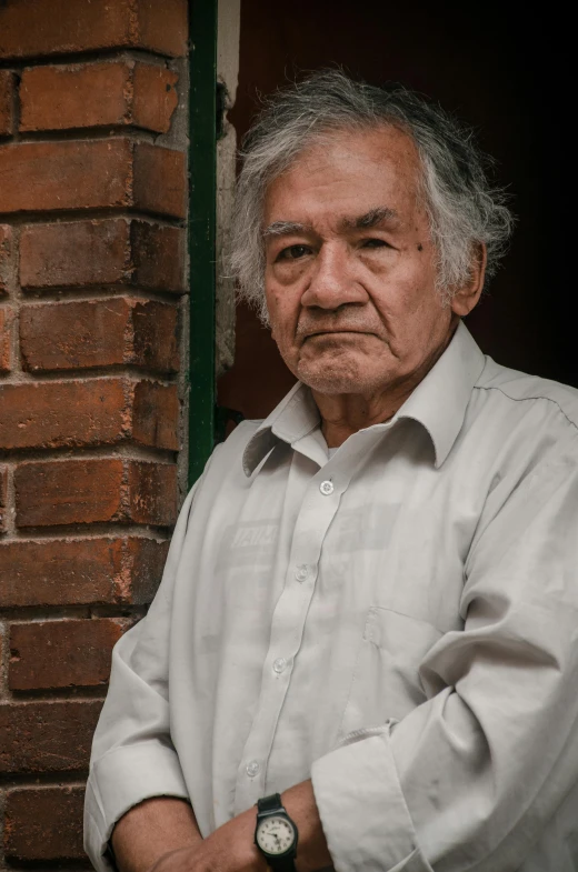 old man stands next to a window in front of a brick building