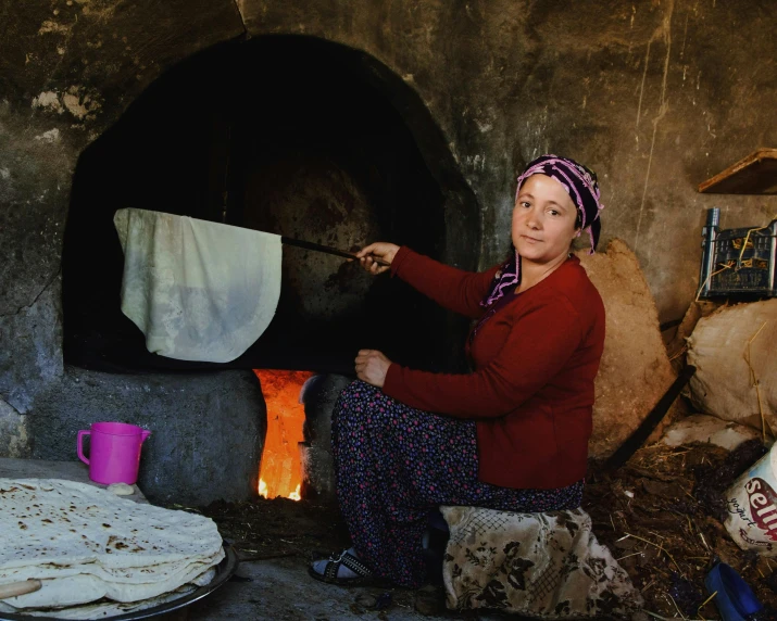 a woman sitting by a fire while putting soing on it
