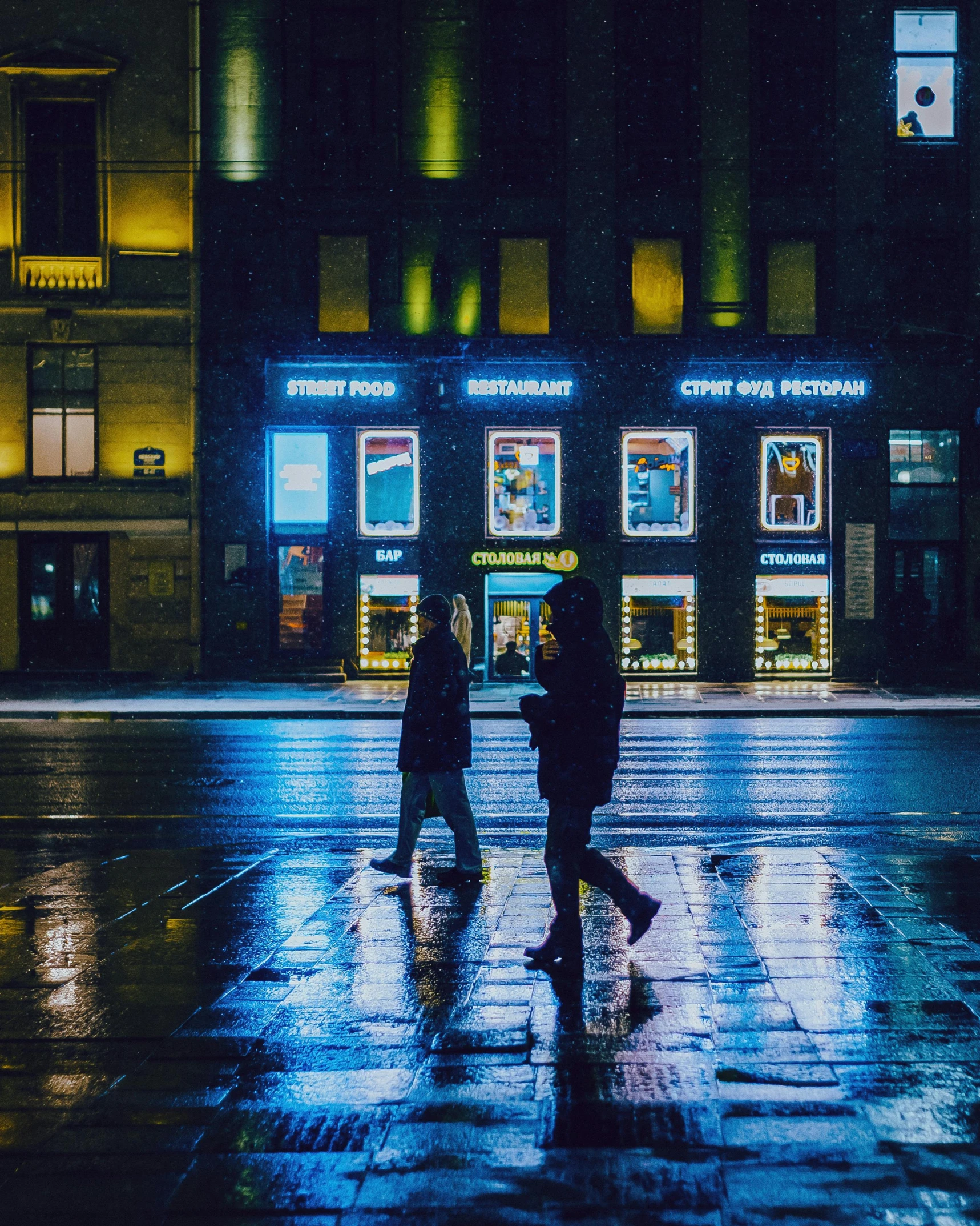 two people in the rain crossing the street