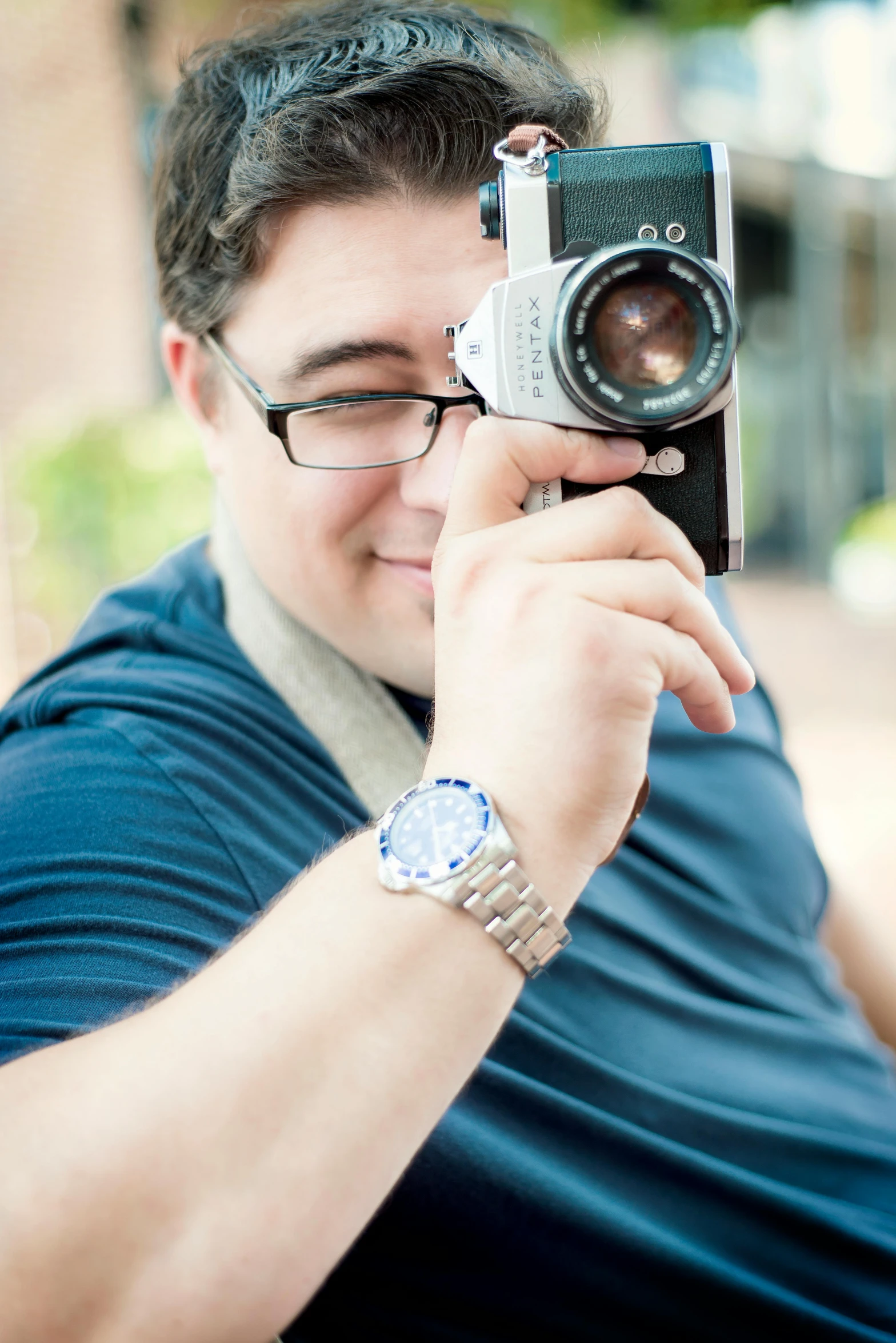 a person wearing glasses is holding up a camera