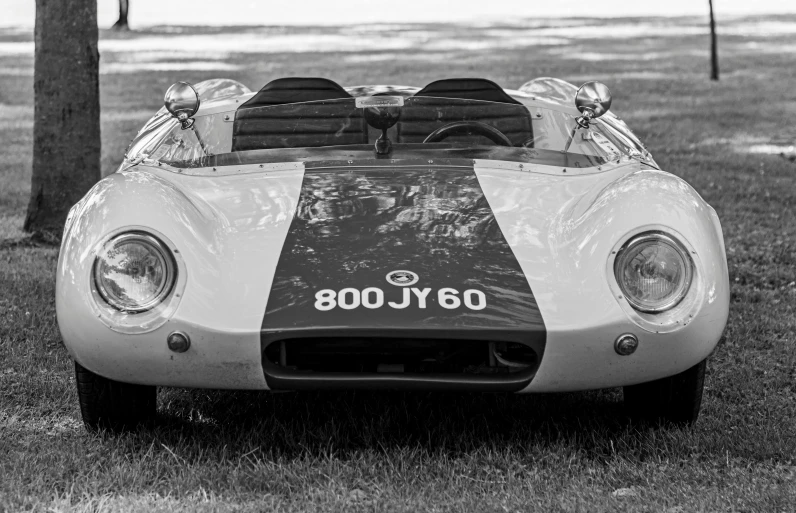 a vintage white and black racing car sitting on grass