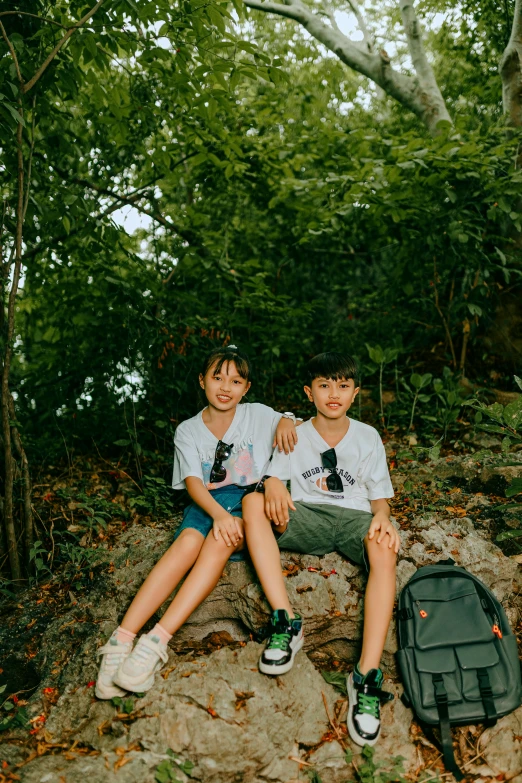 two boys are posing with their skateboards in the woods