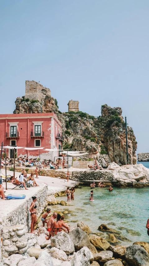 people sit around and relax on the rocks by the sea