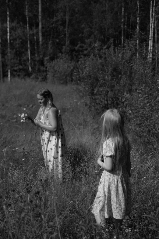 two girls are walking through tall grass