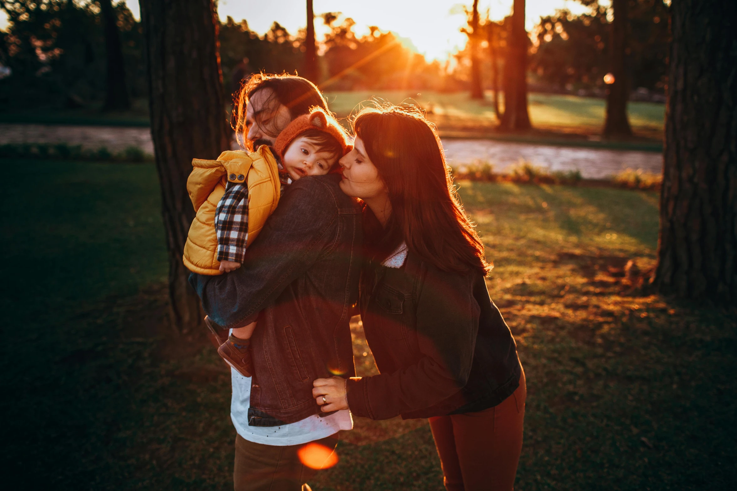 the couple kiss as the sun sets behind them