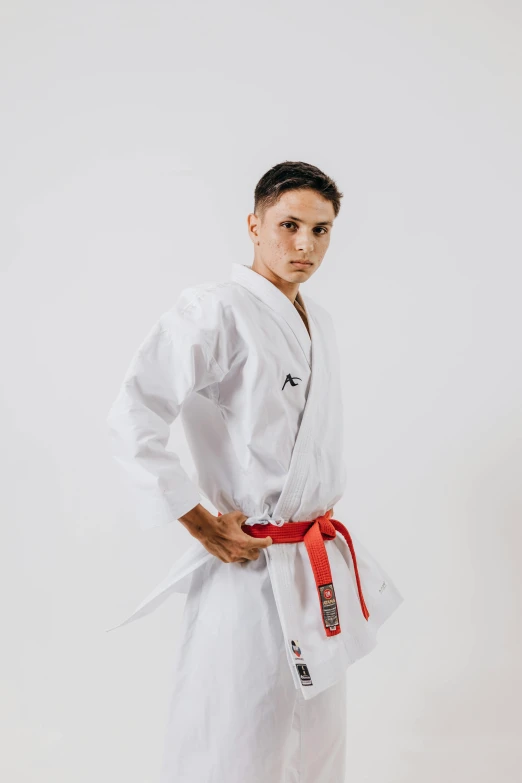 a young man in white stands with his hand on his hip