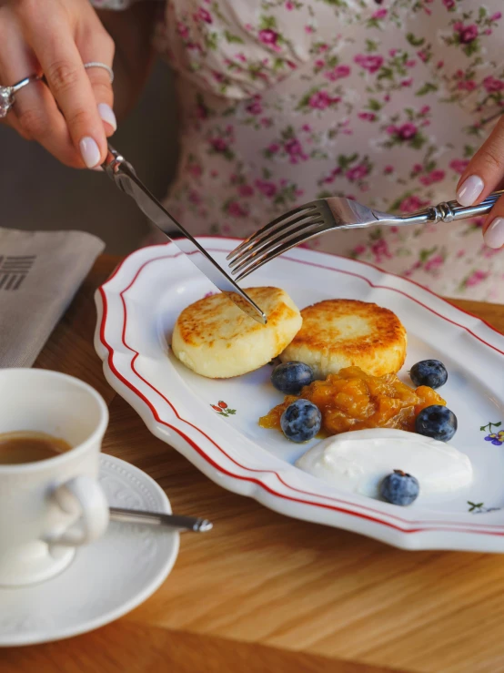 a woman eating pancakes and berries on the plate