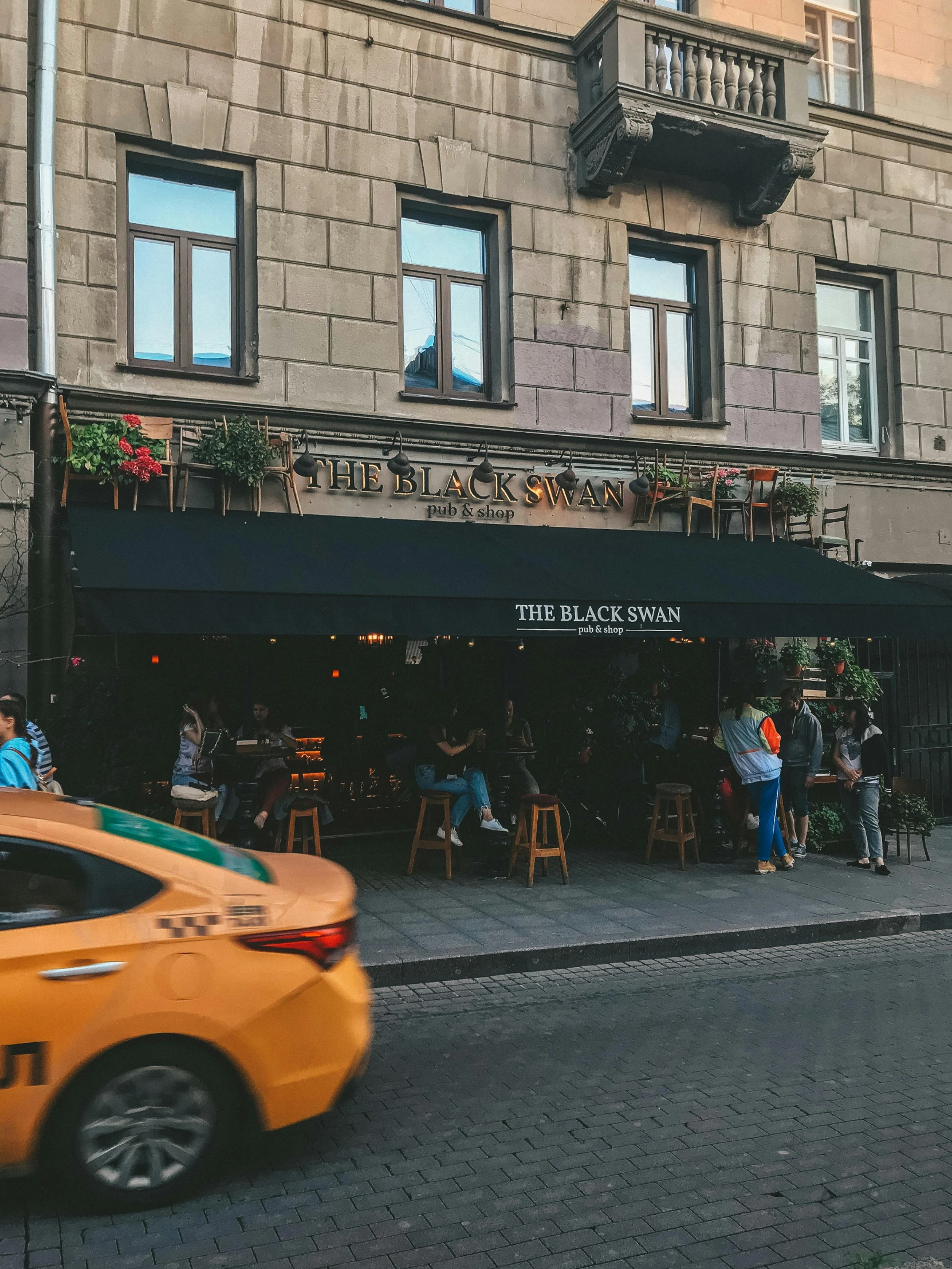 people are sitting in front of a cafe at an intersection