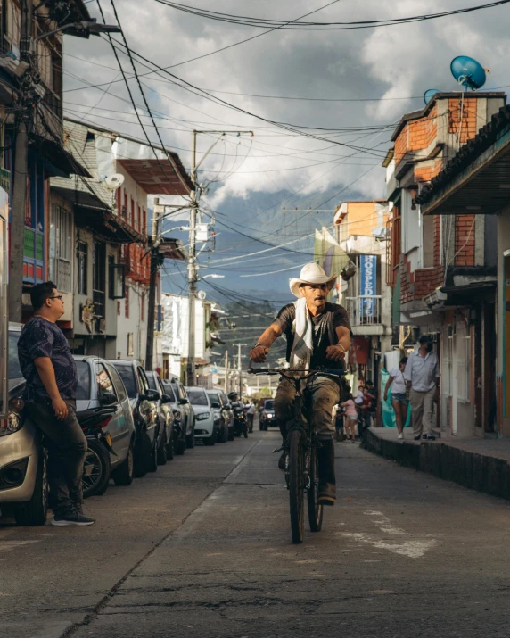 people in street riding motorcycles near houses and cars