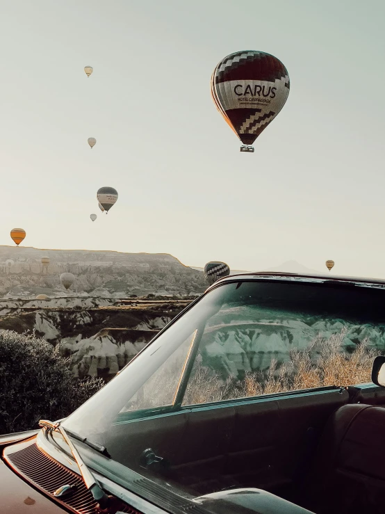 a group of  air balloons flying above a car