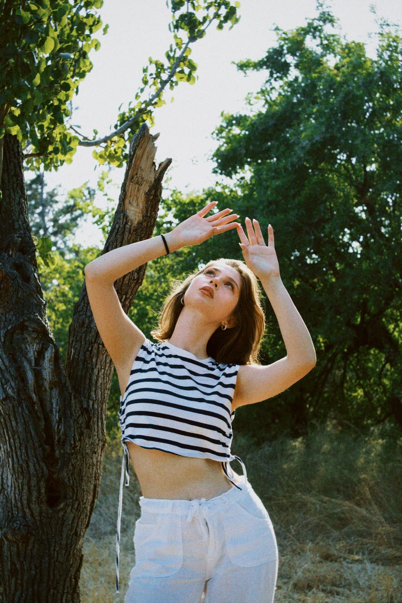 woman in striped top near a tree doing yoga