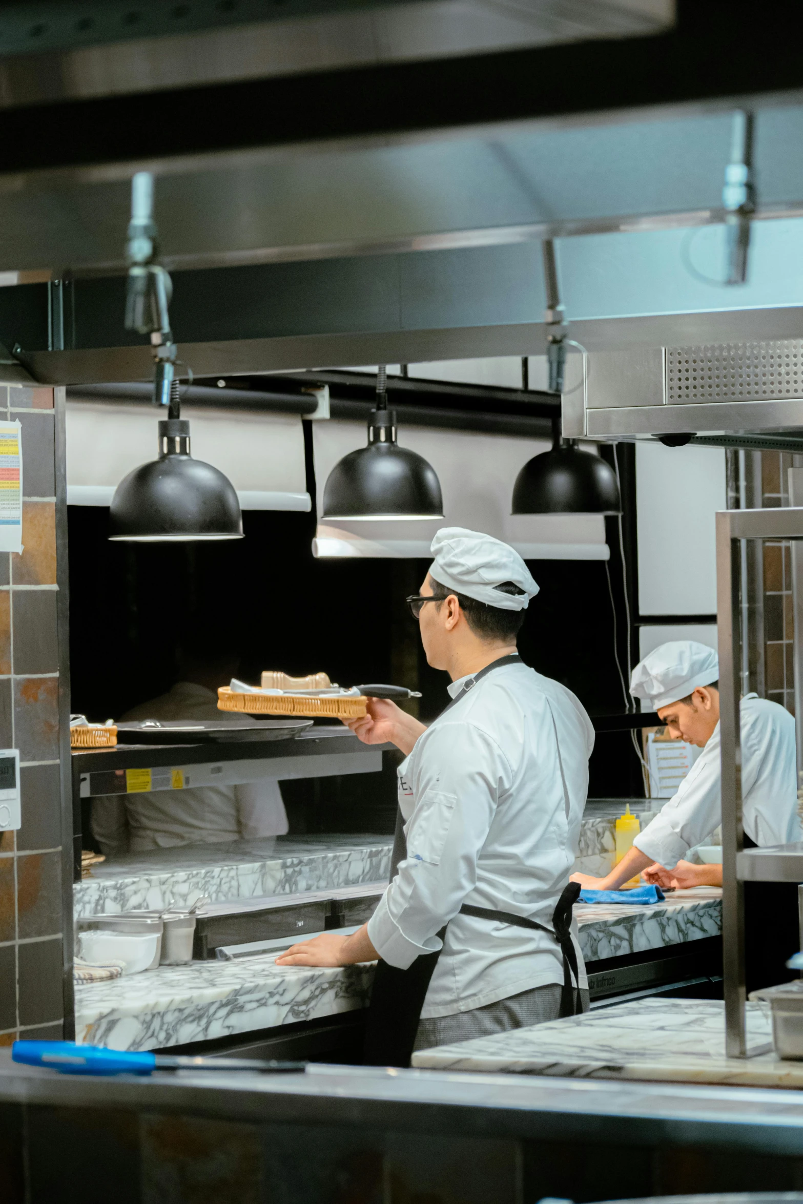 two chefs in a kitchen making pizzas