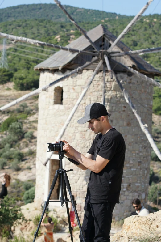 a man using a tripod on top of a rock