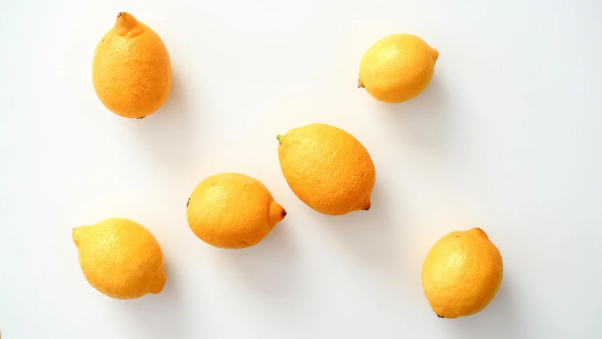 seven oranges laid out in rows on a white surface