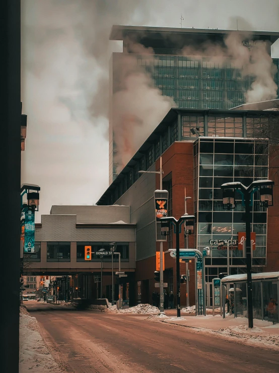 smoke billowing out the clouds above some buildings and snow
