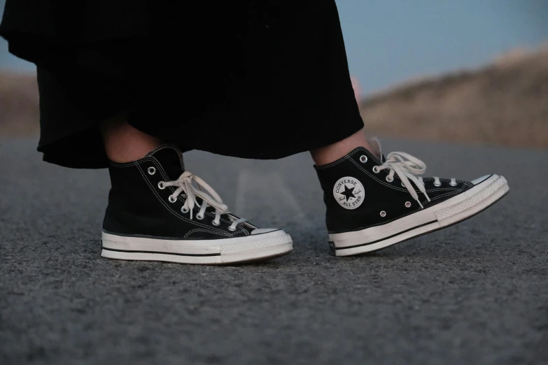 a woman wearing black and white converse shoes