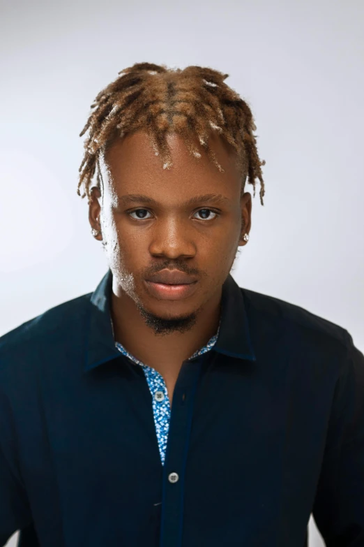 a man with long blonde dreadlocks standing in front of a white background
