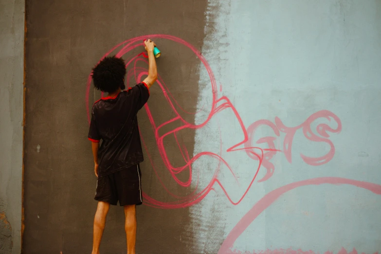 the boy is drawing graffiti on the wall with a roller toy