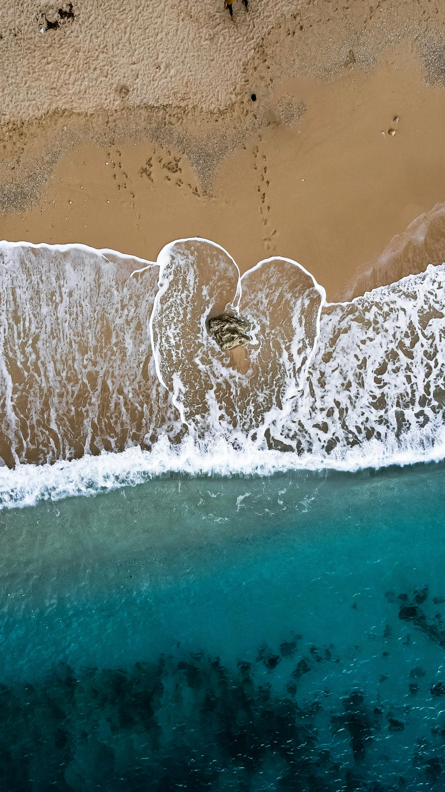 an aerial view of the ocean with sand and waves