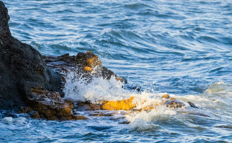 a rock in the ocean with a splashing wave on it