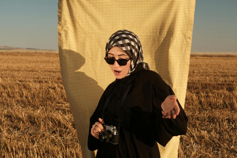 a woman standing in a field holding onto an object with her hand