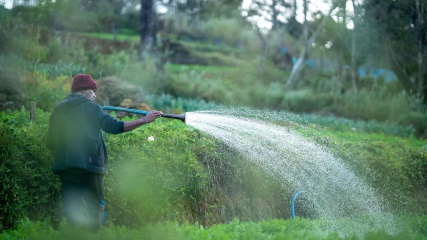 man in a red hat spraying water out on a field