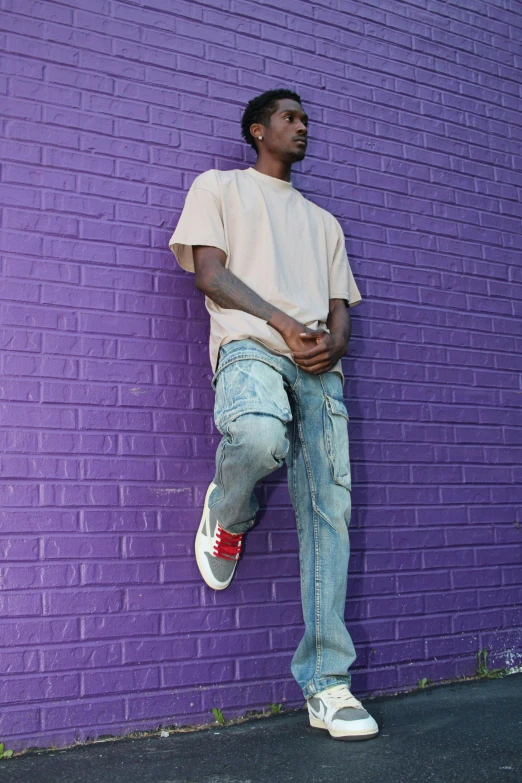 man standing on ledge with head up against purple wall