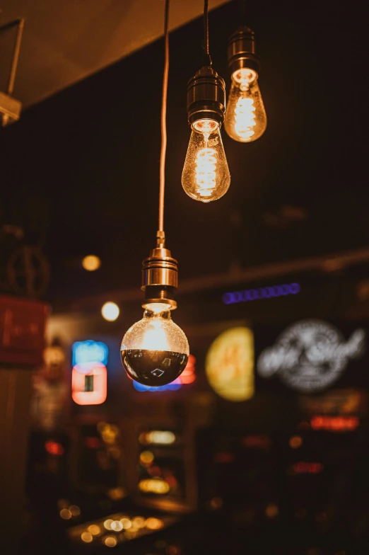 several lights hanging from a bar next to a neon sign