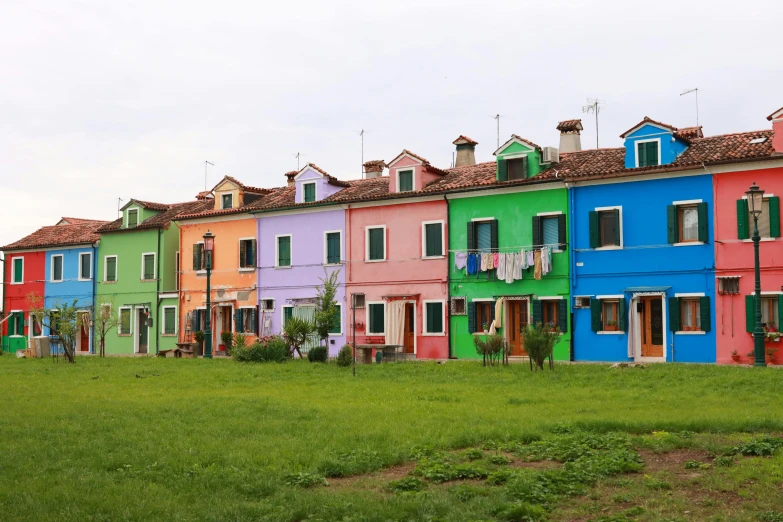 rows of multi colored homes in front of each other on a grassy field