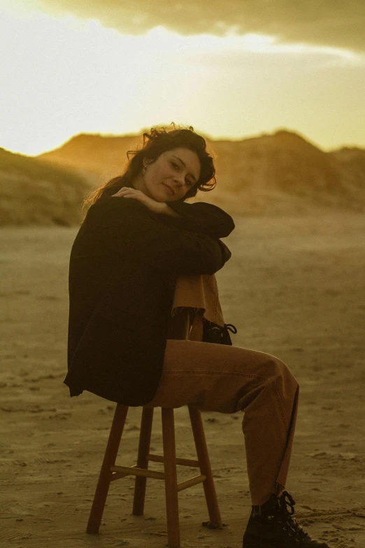 a woman sits on a chair in the desert