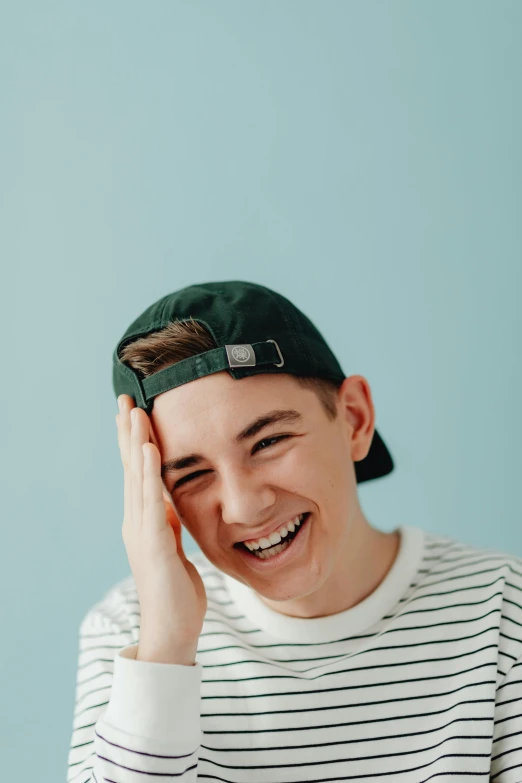 a young man wearing a green baseball cap smiling