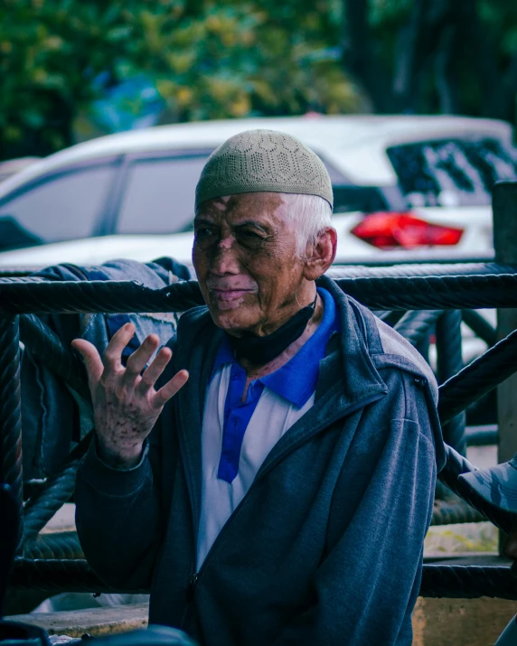 an older man holds up his hand in front of him