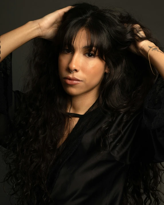 a woman with curly hair holding her hands behind her head